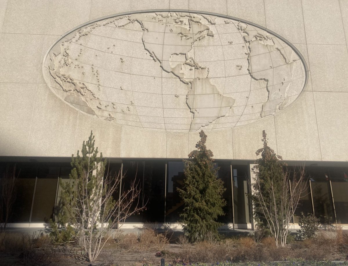 Sunlit concrete oval world map relief on the south side of the LDS Church Office Building, showing North and South America with latitude and longitude grid lines.