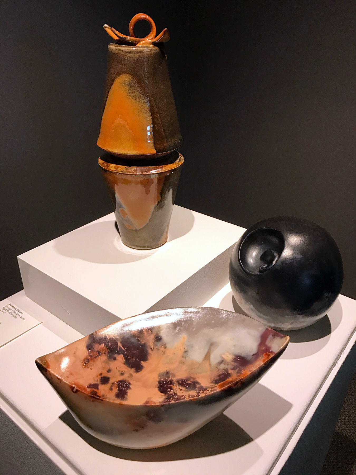 “Orange Vase/Urn” (2017, 15 × 6 in), “Patientia” (2016, 7 in dia.), and “Hunter’s Moon I” (2016, 8 × 6 × 9 in) by Barbara Ellard