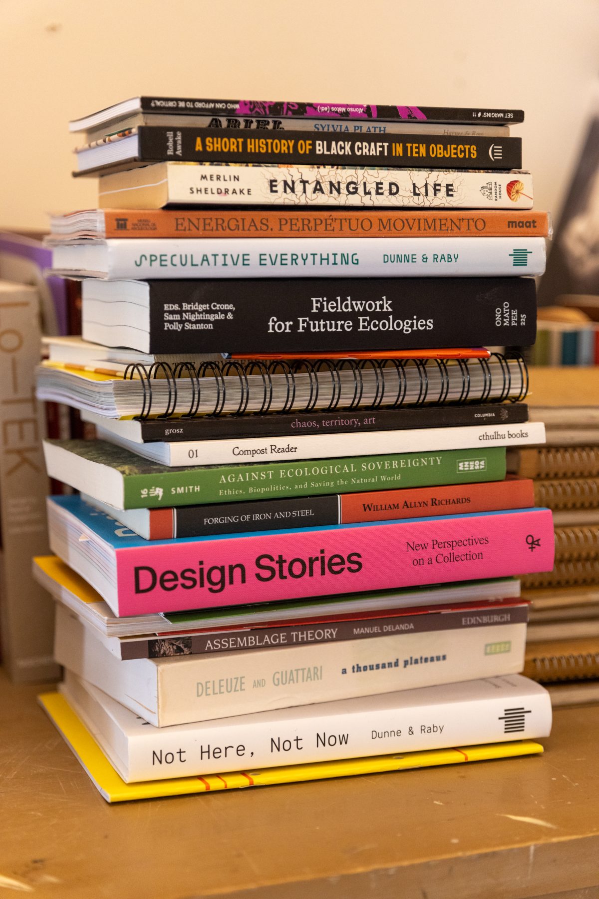 Tall stack of art, design, ecology, and theory books arranged on a tabletop inside Books & Supply.