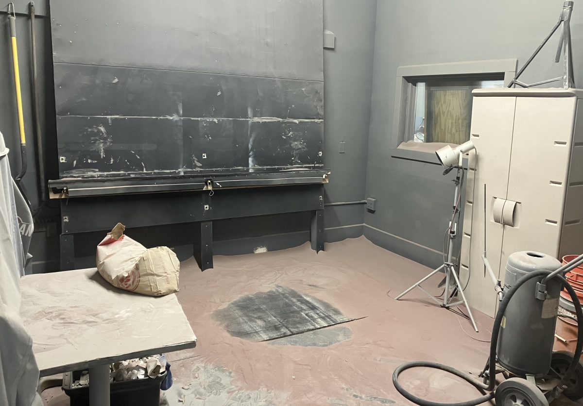 Sandblasting room with equipment, hoses, and a floor covered in abrasive media at Studio-de-Verre.